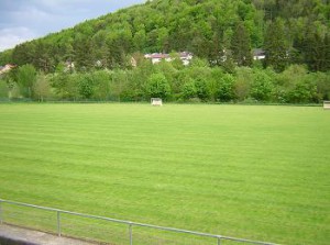 Der Sportplatz des SV Mühlen mit bewaldetem Hang im Hintergrund